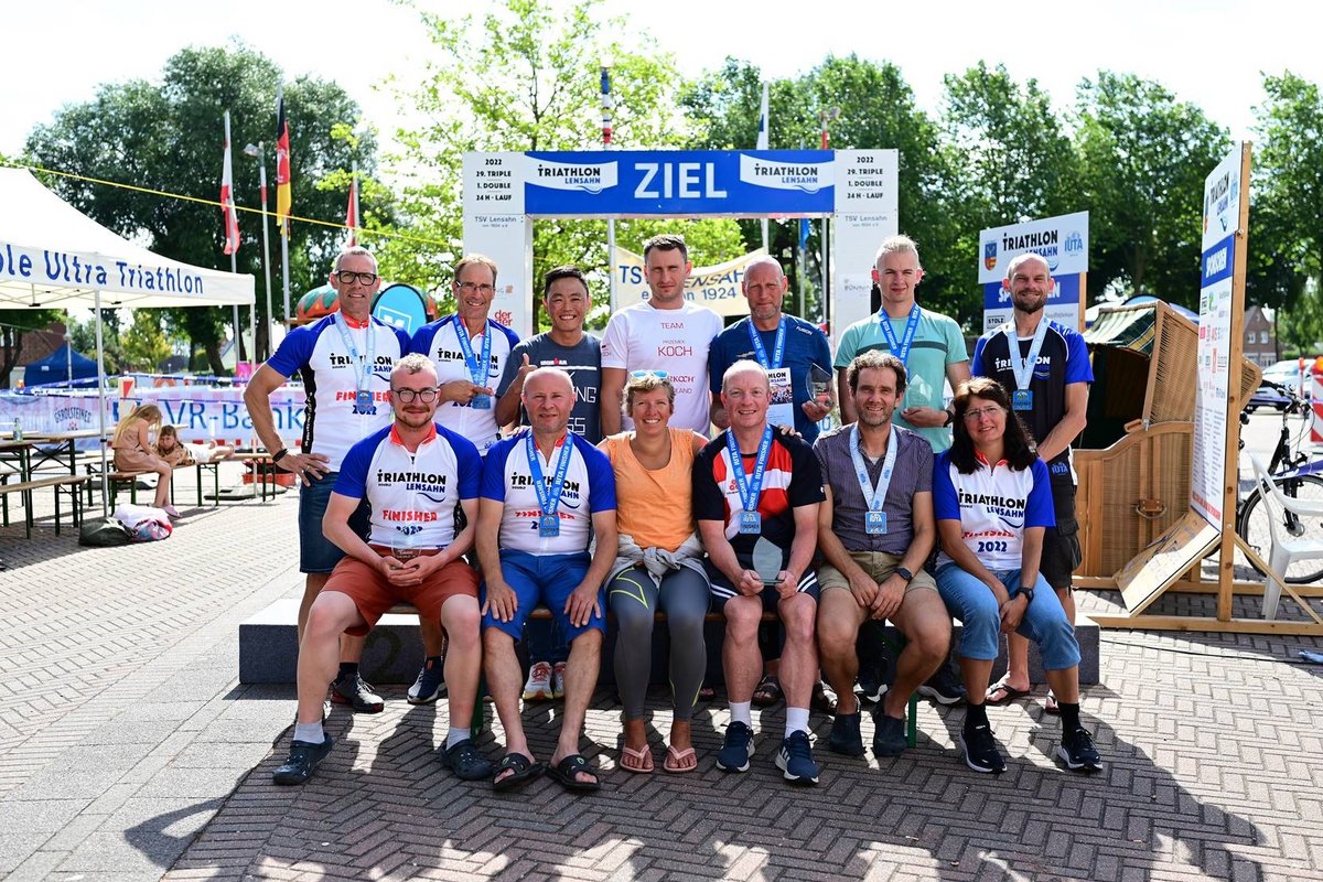 Teilnehmer des Double Ultra Triathlons posieren für ein Foto auf dem Schützenplatz Lensahn