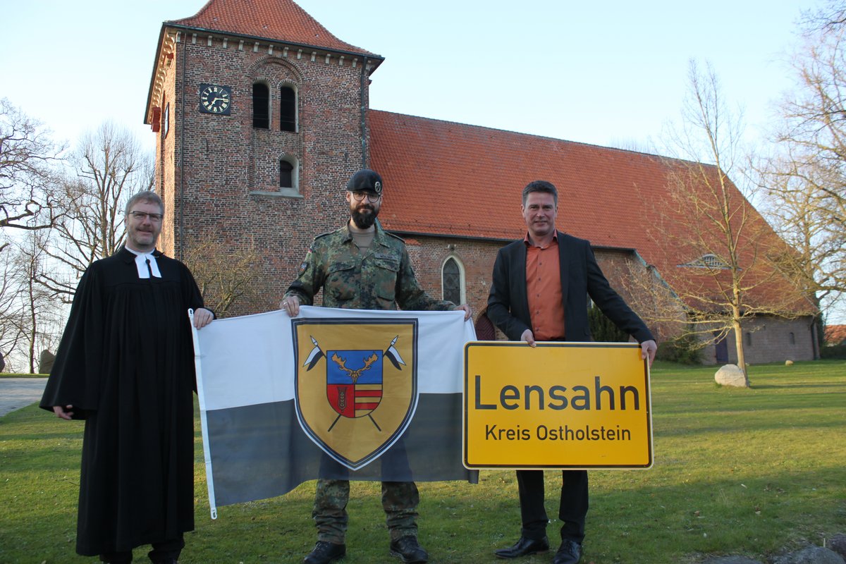 Pastor Reimann, Soladat der Patenkompüanie und Bürgermeister Robien stehen vor der Kirche